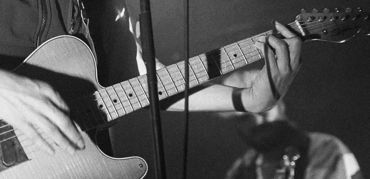 Photo en noir et blanc gros plan sur une guitare durant un concert