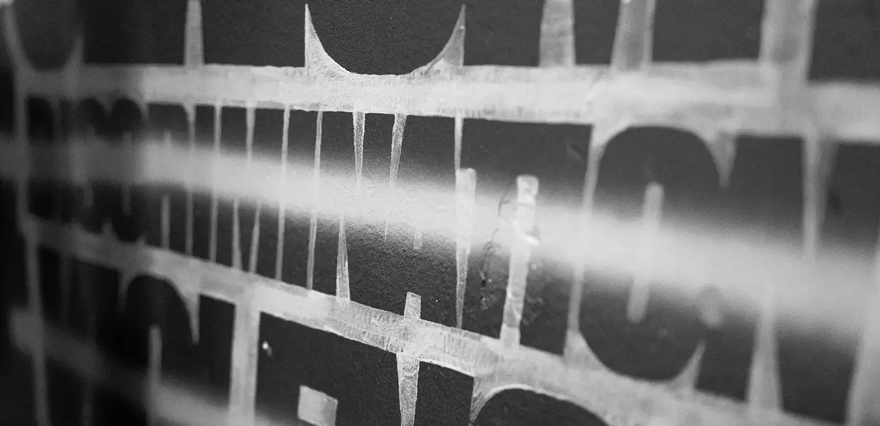 Photo en noir et blanc du mot Discrimination tracé sur un mur