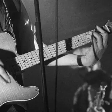 Photo en noir et blanc gros plan sur une guitare durant un concert
