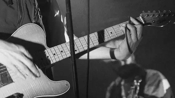 Photo en noir et blanc gros plan sur une guitare durant un concert