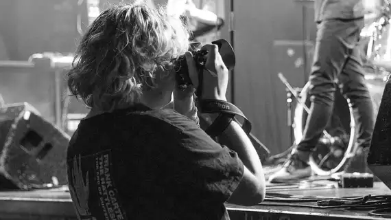 Photo en noir et blanc d'une photographe lors d'un concert