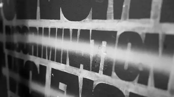 Photo en noir et blanc du mot Discrimination tracé sur un mur