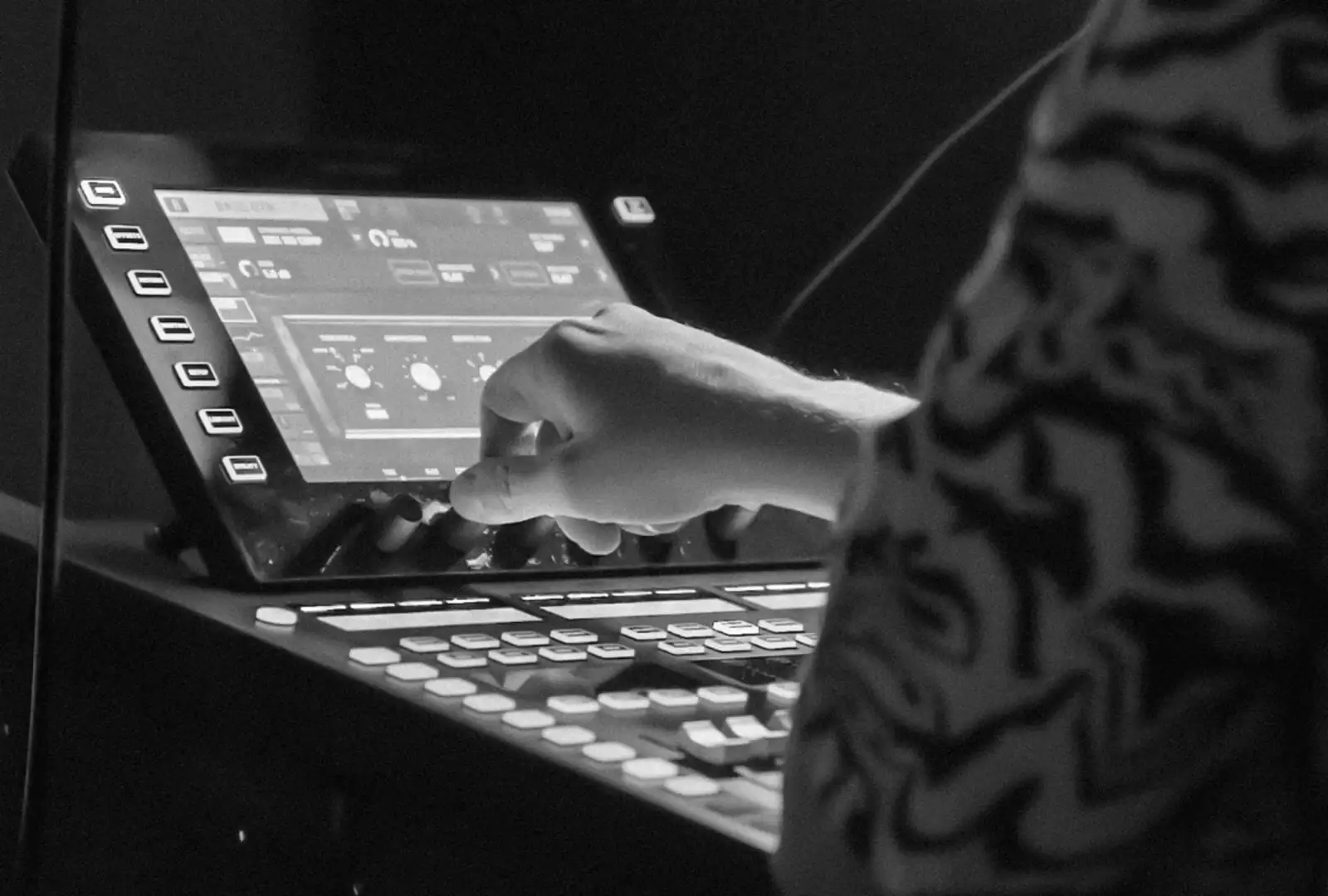 Photo en noir et blanc d'une main sur une console lumière